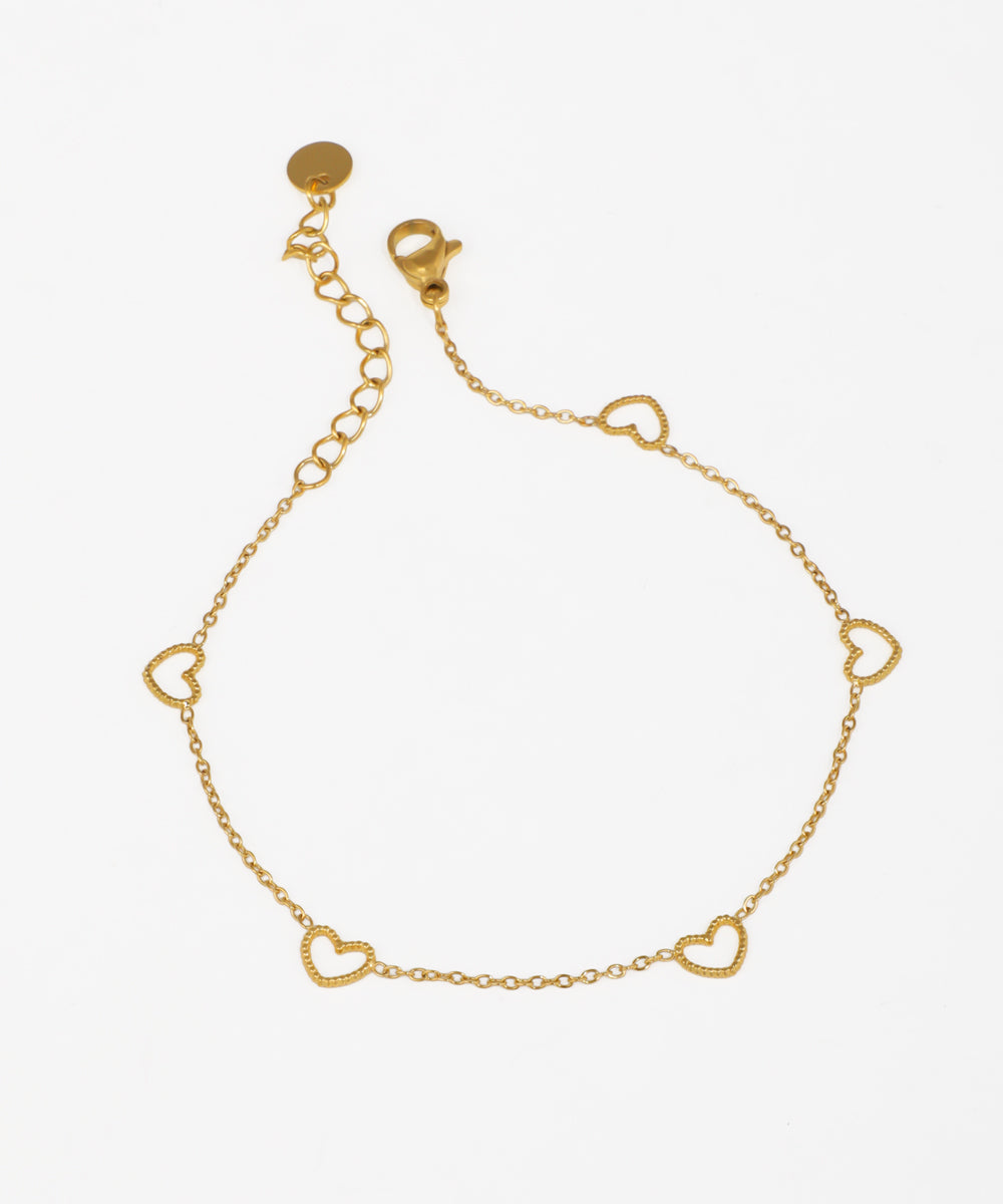 Gold-tone bracelet with dainty chain and scattered open heart charms with textured edges