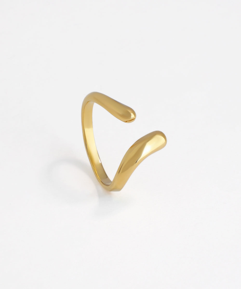 Polished gold-tone open ring with a sculptural, fluid wave design.