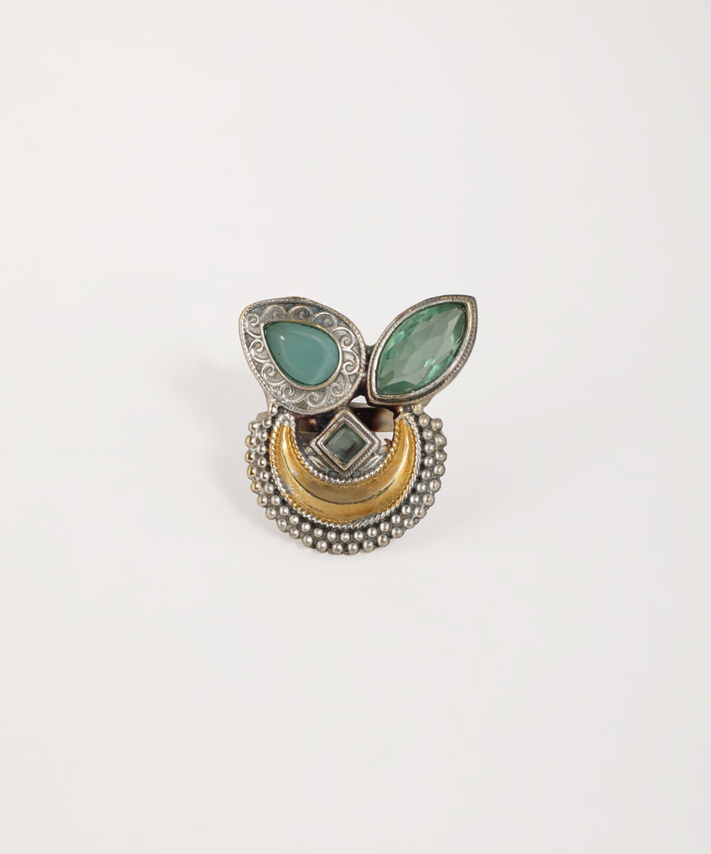 Decorative ring with green stones and gold accents on a white background