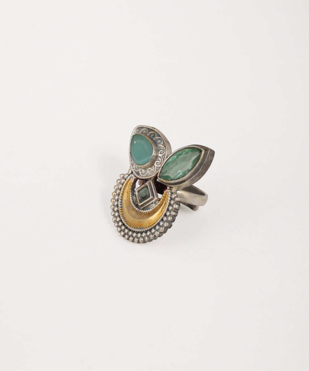 Decorative ring with green gemstones and gold accents on a white background