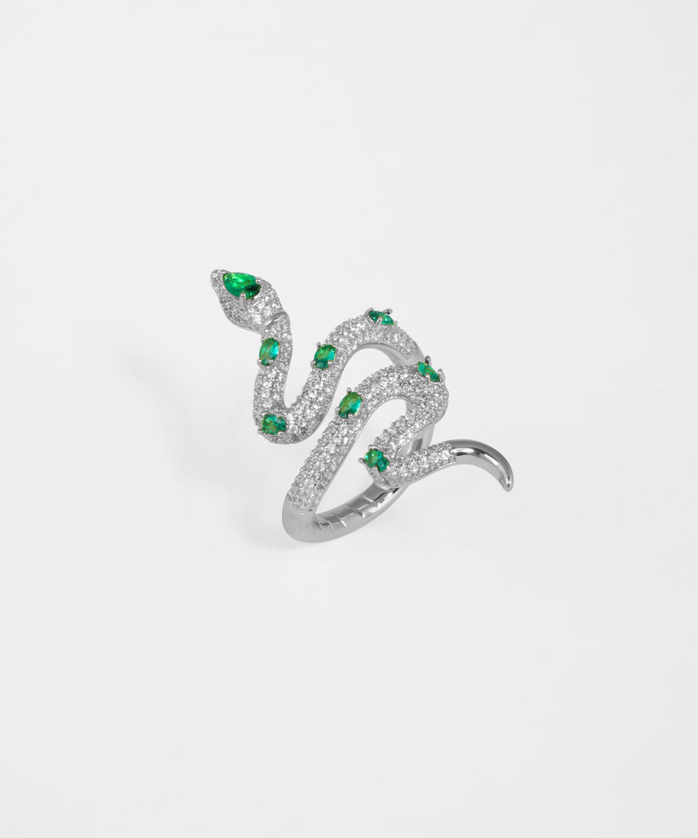 Silver snake-shaped ring with green gemstones on a light gray background