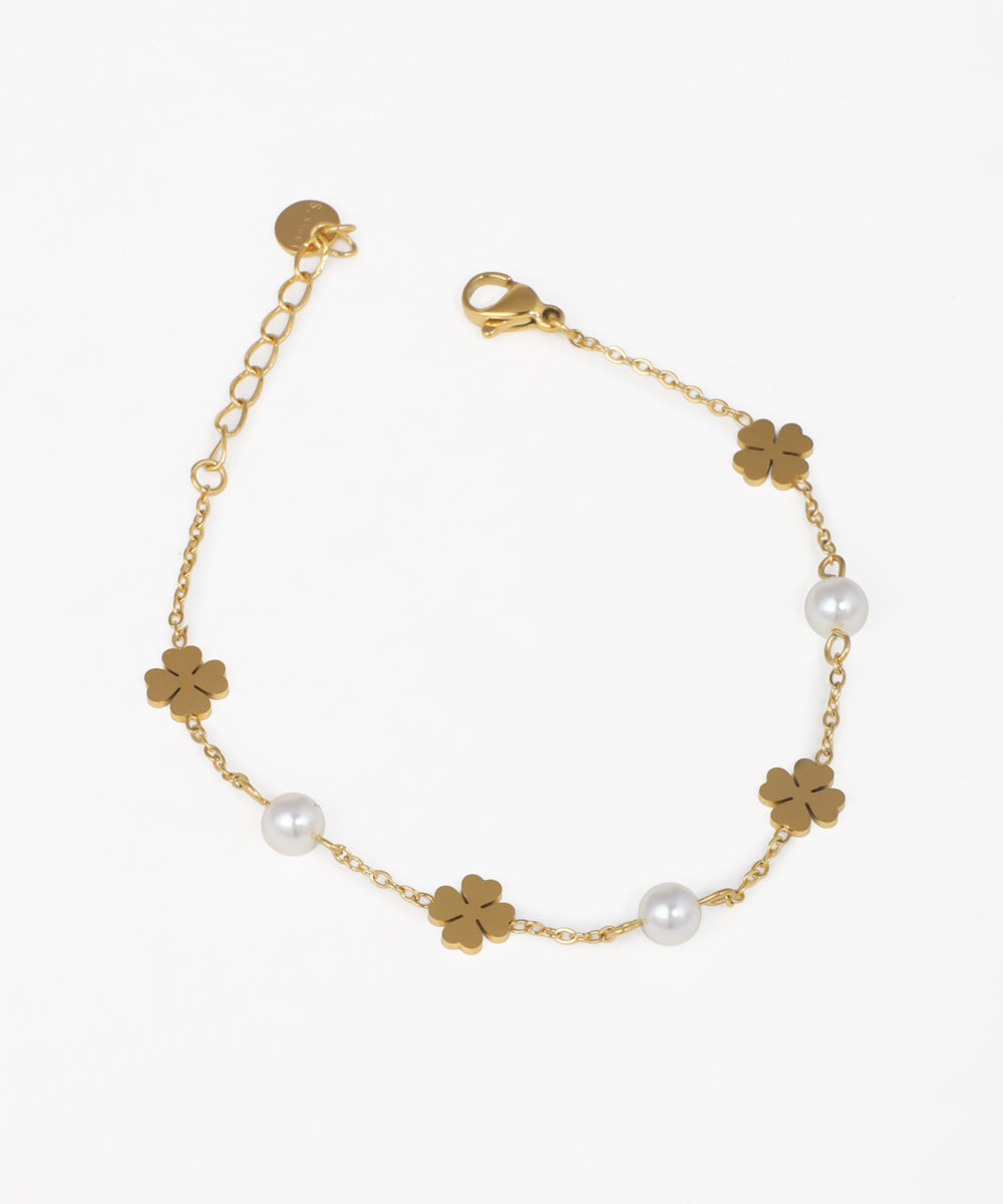 Gold-tone bracelet with four-leaf clover charms and white faux pearls on a delicate chain with a lobster clasp