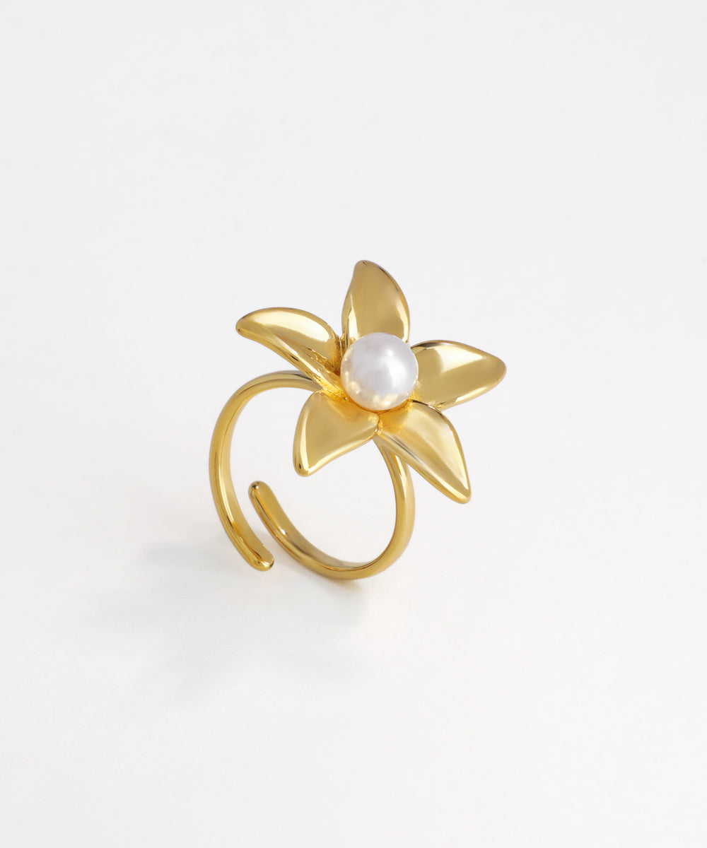 Gold-tone ring with sculpted five-petal flower design and a central faux pearl, open adjustable band.