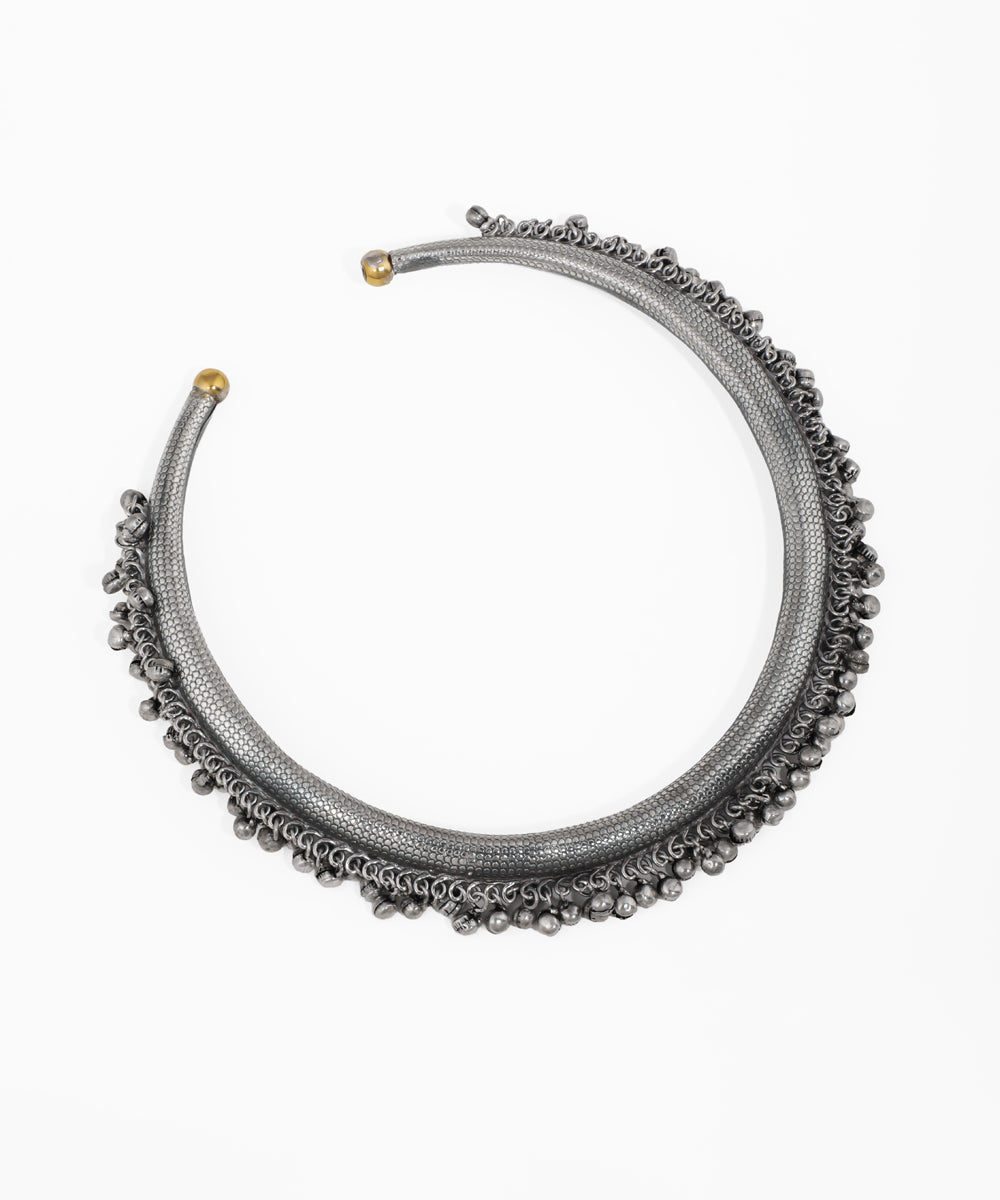 Oxidized hasli necklace with textured surface and multiple rows of small metal ghungroo beads.