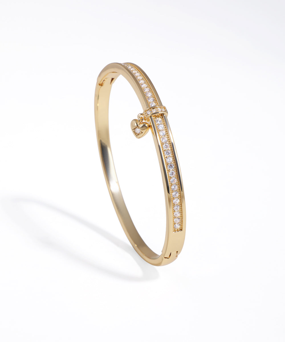 Gold-tone bracelet with half-pave CZ stones and a small heart charm detail.