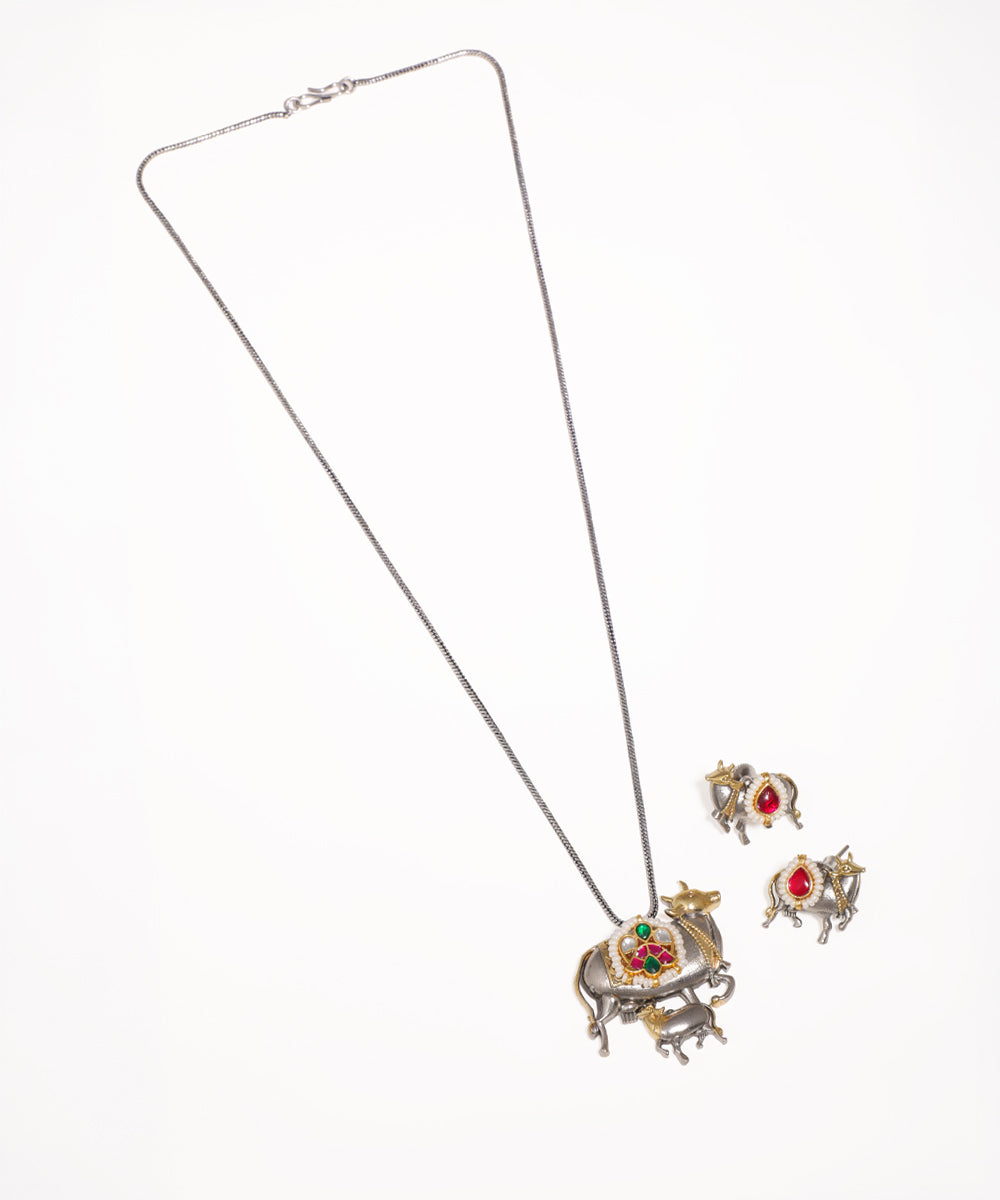 Oxidised necklace and earrings set with cow motif, red and green stones, and faux pearls.