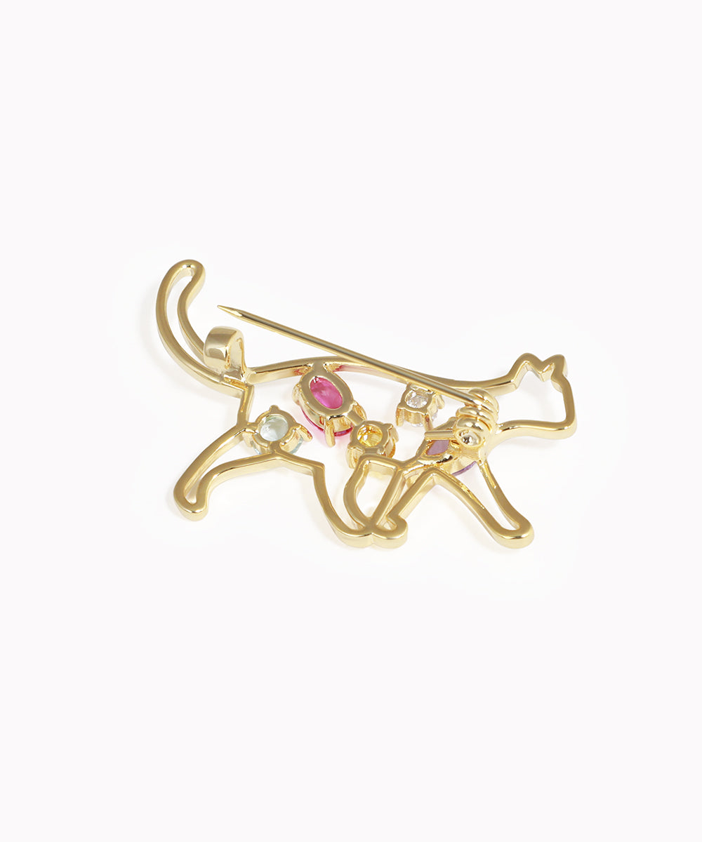 Gold bow and arrow brooch with colorful gemstones on a white background