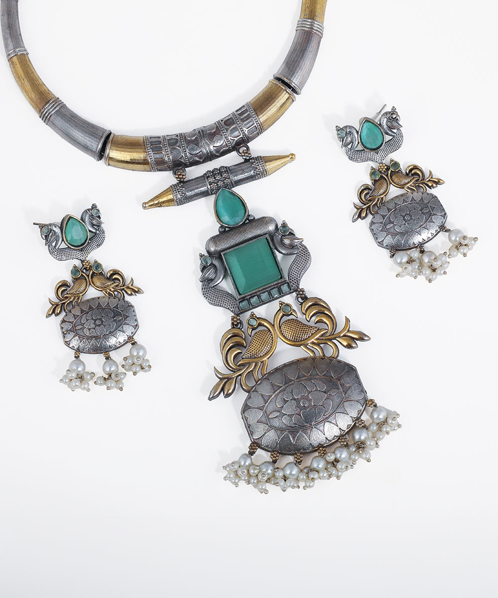 Ornate silver and gold necklace with green gemstones on a white background