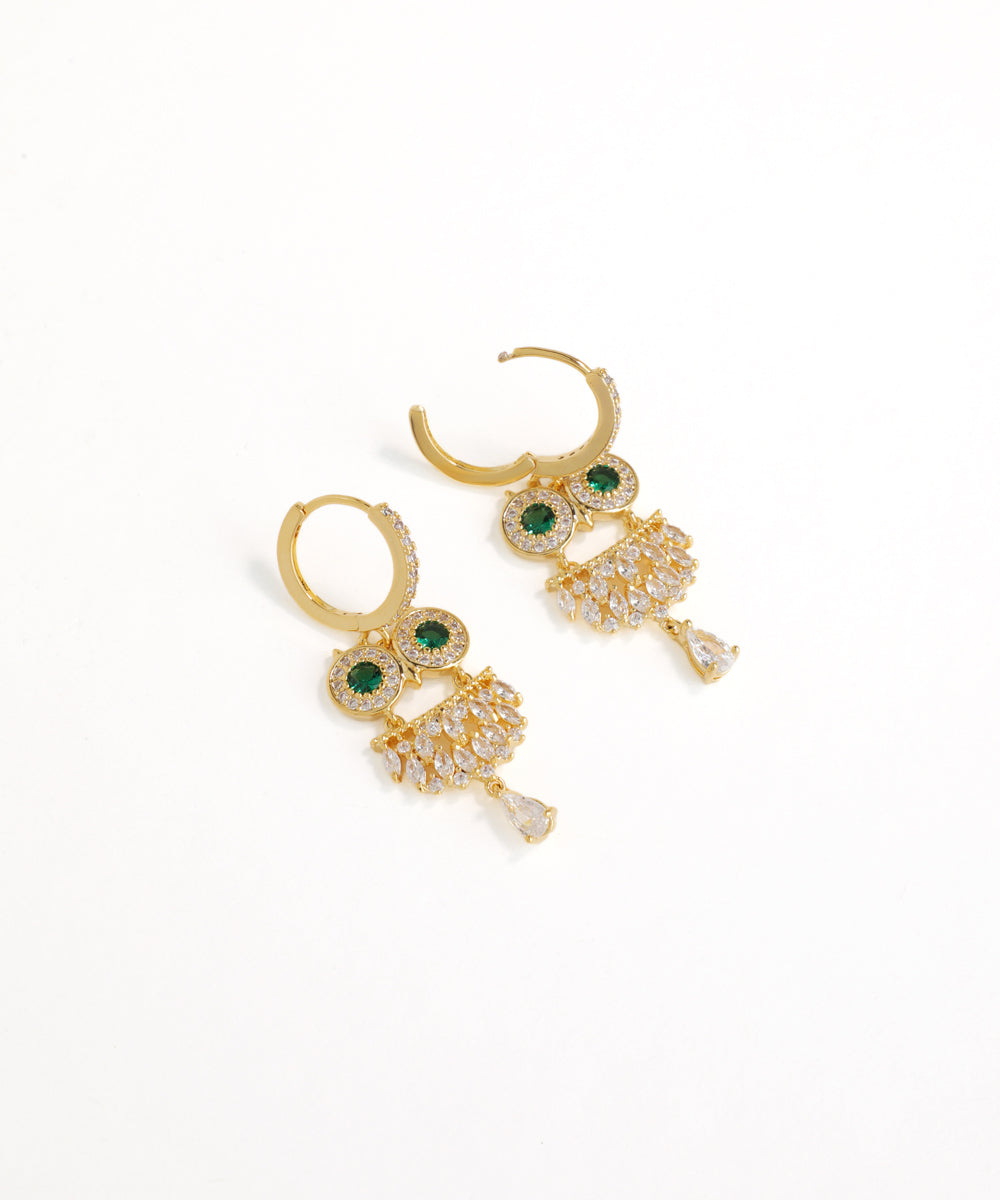 Gold earrings with green gemstones on a white background