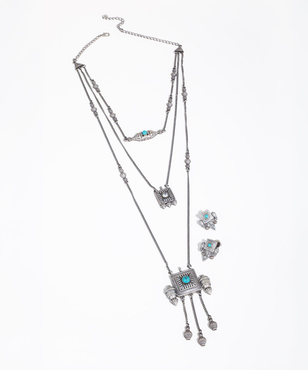 Silver-tone layered necklace with geometric pendants, blue stones, and textured details