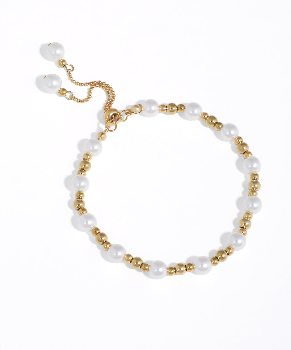 Gold-tone bracelet with alternating white faux pearls and metal beads, featuring an adjustable bolo clasp.