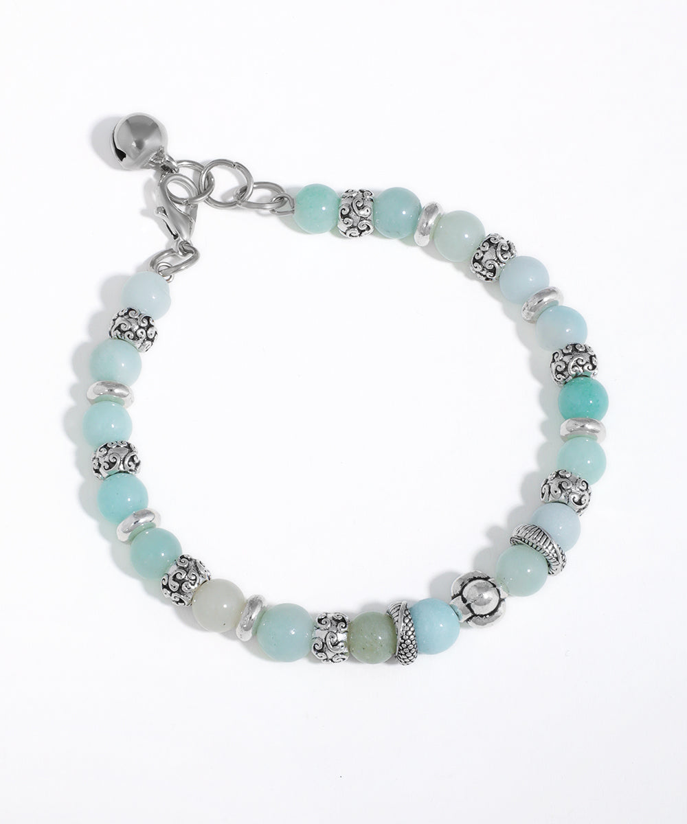 Silver-tone beaded bracelet with aqua, mint, and pale green glass beads, featuring ornate spacer beads and a bell charm.