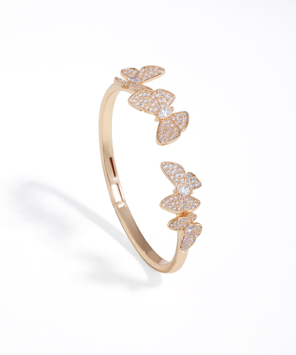 Rose gold open ring with butterfly designs on a white background