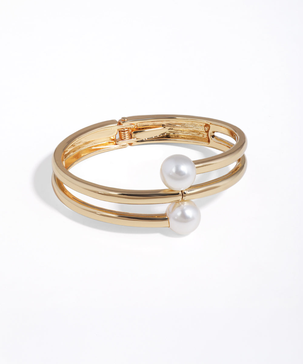 Gold bracelet with pearl accents on a white background