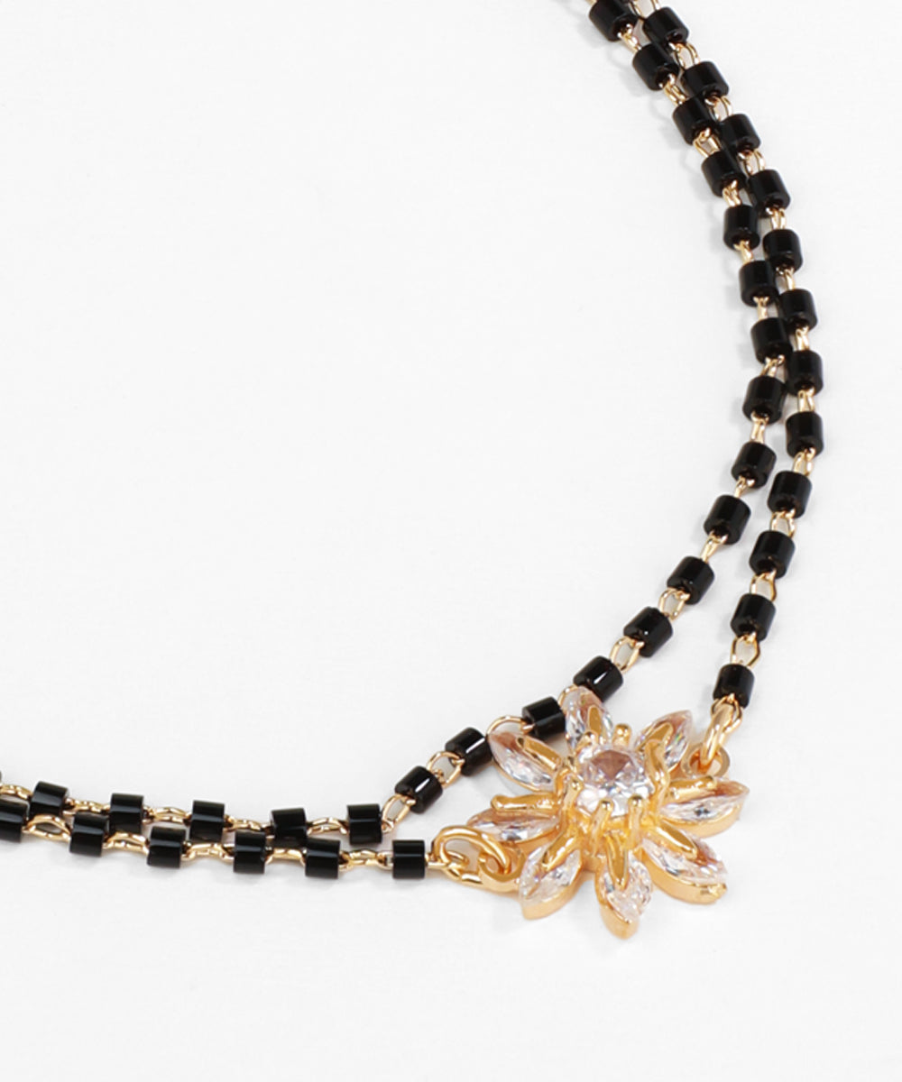 Necklace with black and rose gold beads and a floral pendant on a white background