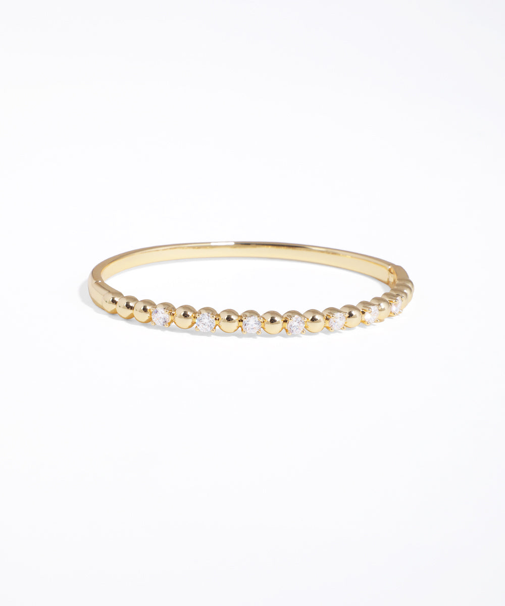 Gold bracelet with small beads on a white background