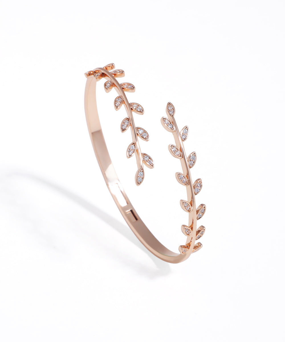Rose gold bracelet with leaf design on a white background