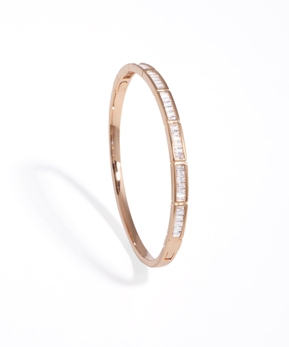 Rose gold bangle with embedded diamonds on a white background