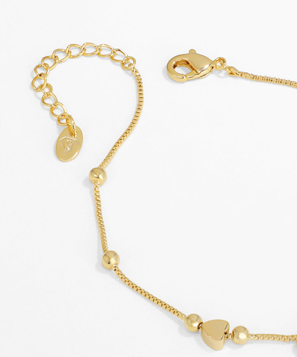 Gold bracelet with heart-shaped beads on a white background