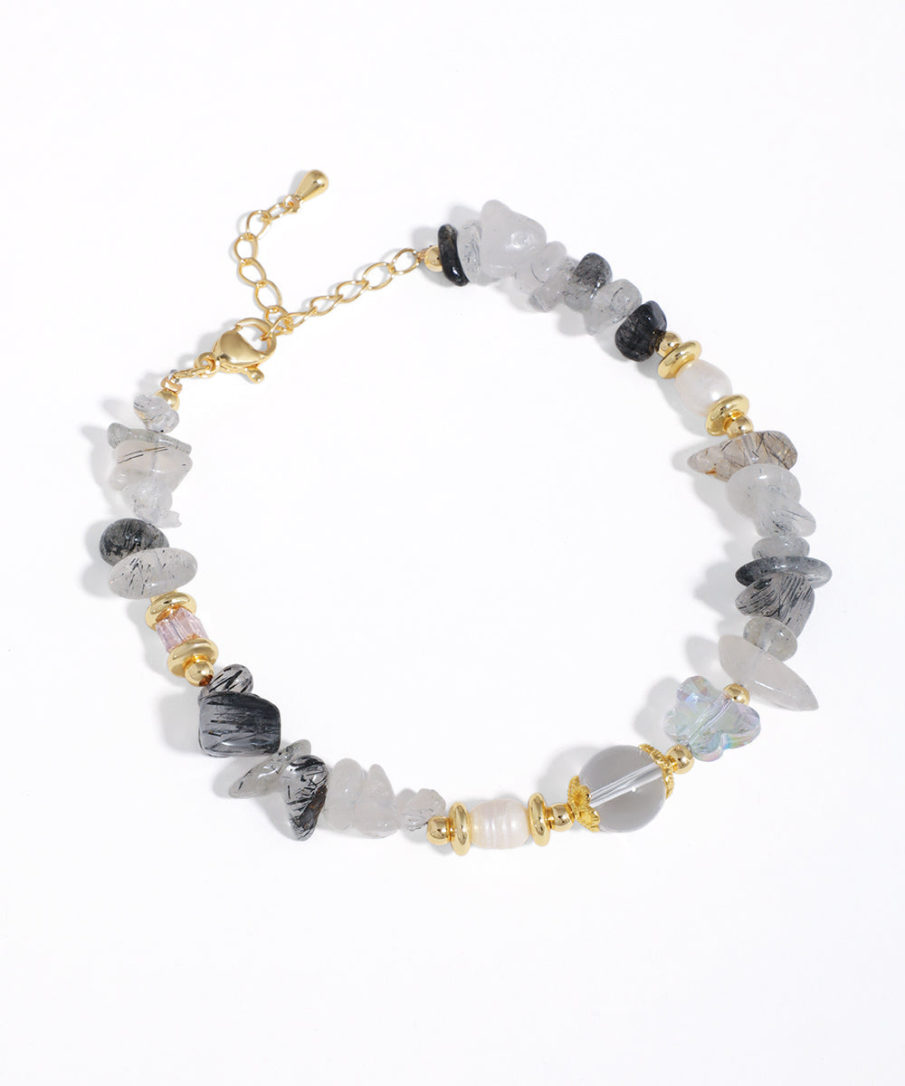 Gold-tone bracelet with grey, black, and clear irregular stone beads, faux pearls, and glass crystals.