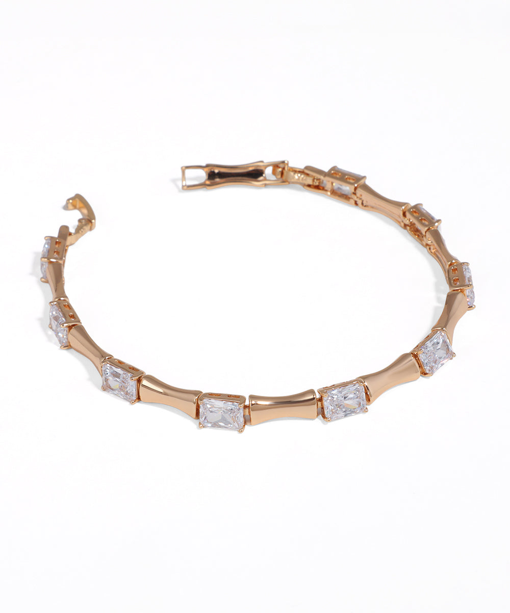 Rose-tone link bracelet with alternating rectangular clear stones and a secure box clasp closure.