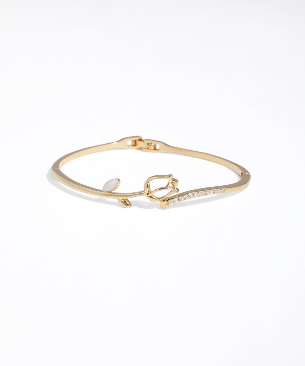 Gold bracelet with heart charm on a white background