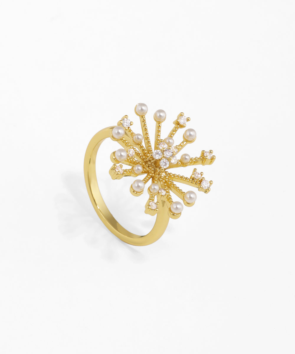 Gold-tone finger ring with a starburst cluster design, adorned with clear CZ stones and small faux pearls.