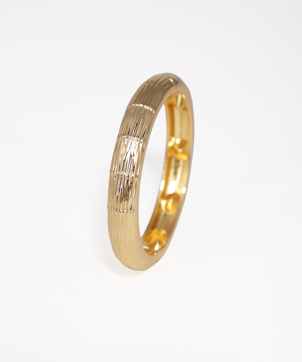Gold ring with a textured design on a white background