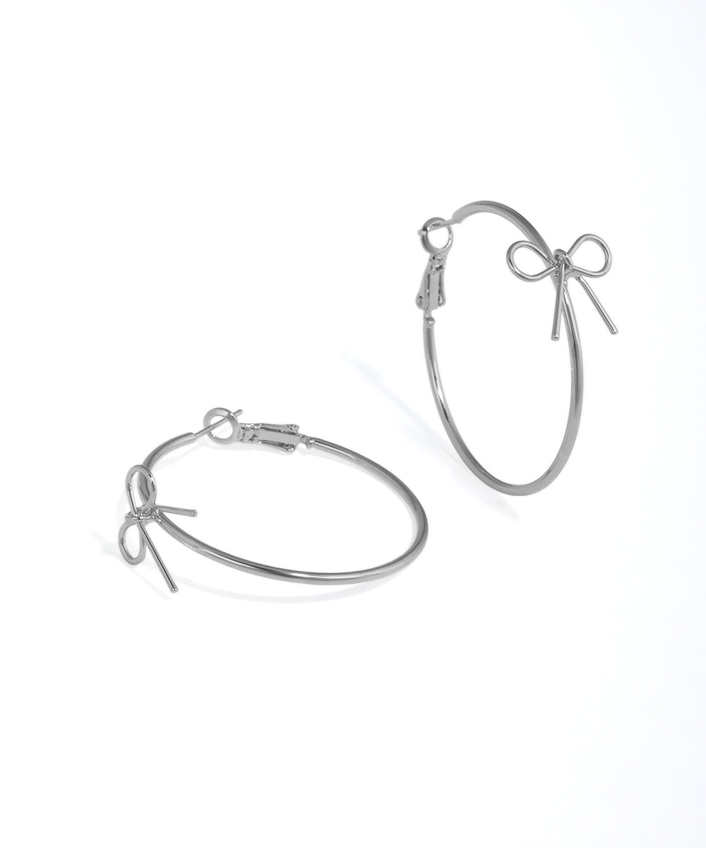 Rhodium finish hoop earrings with a small bow charm