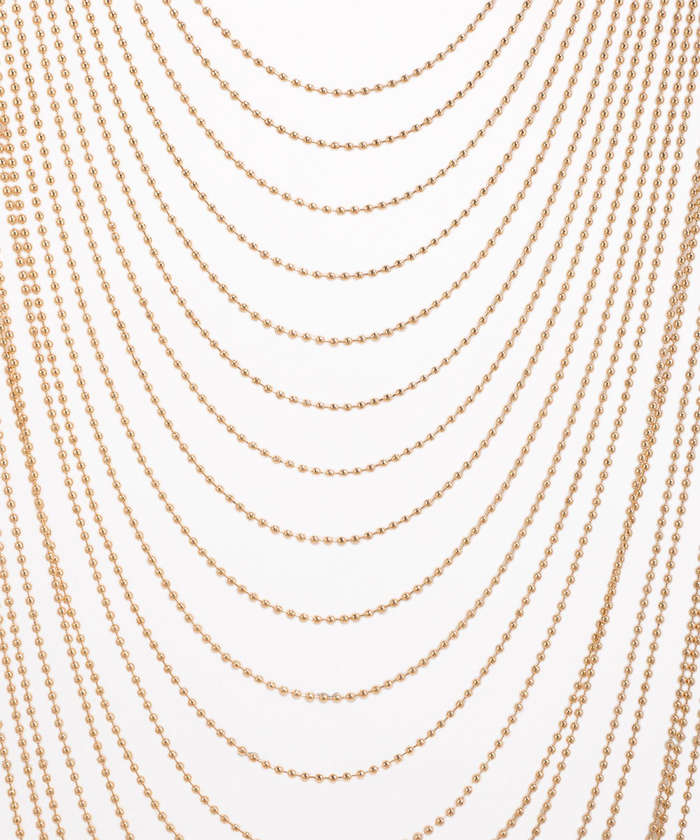 Multiple strands of gold beads on a white background