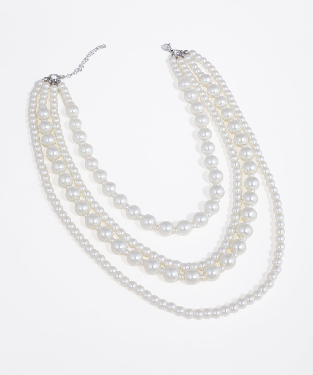 Silver-tone necklace with four cascading strands of faux pearls in varying sizes.