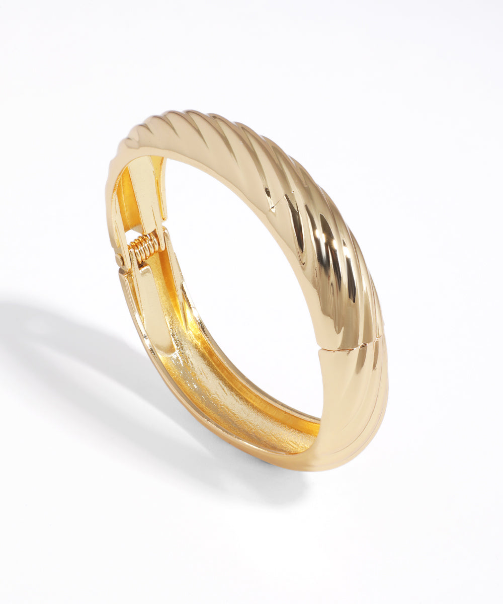 Gold ring with a textured design on a white background