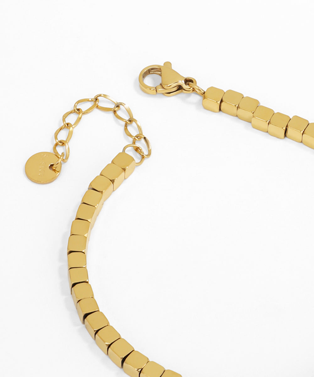 Gold beaded bracelet with a clasp on a white background