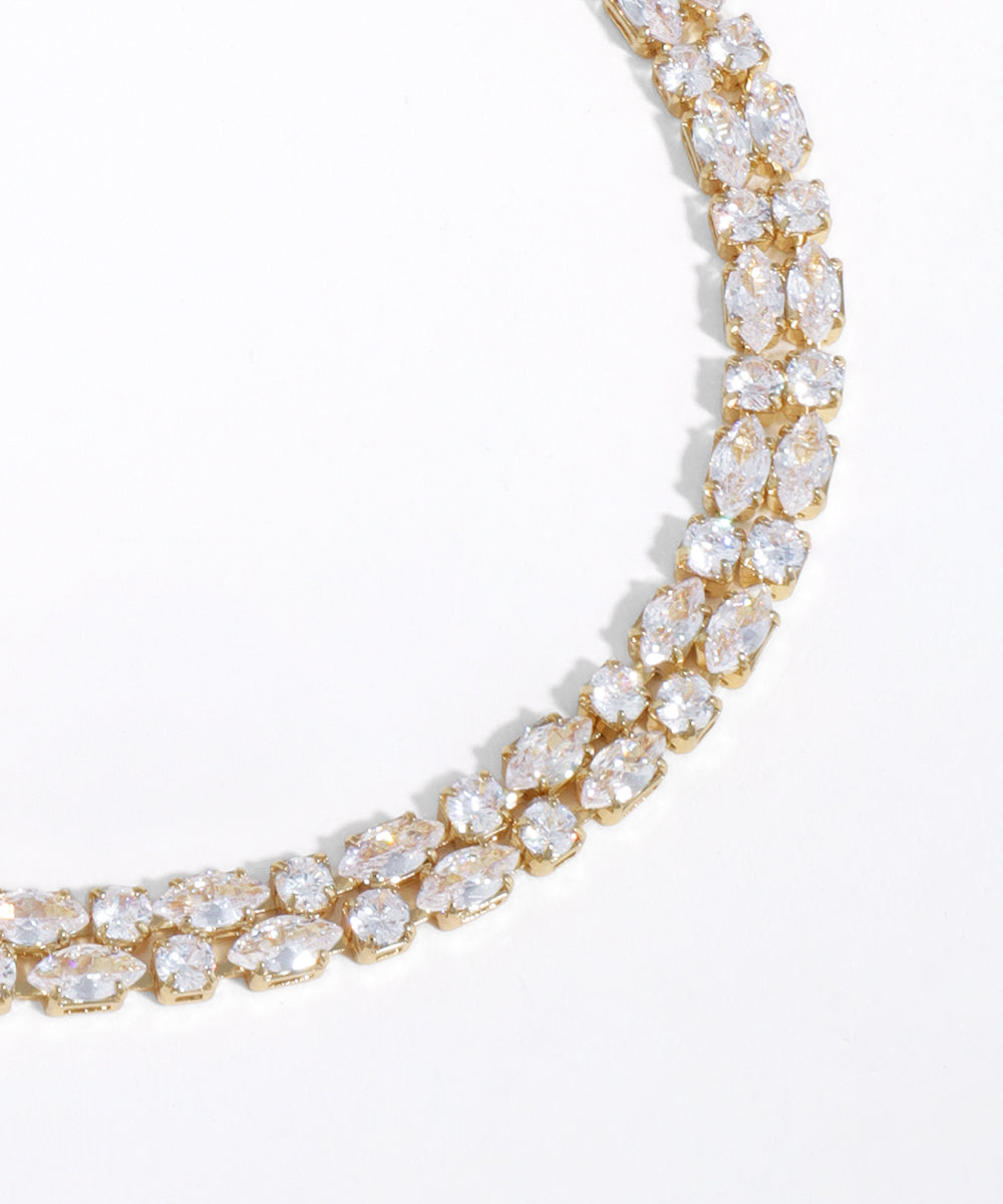 Gold necklace with clear gemstones on a white background