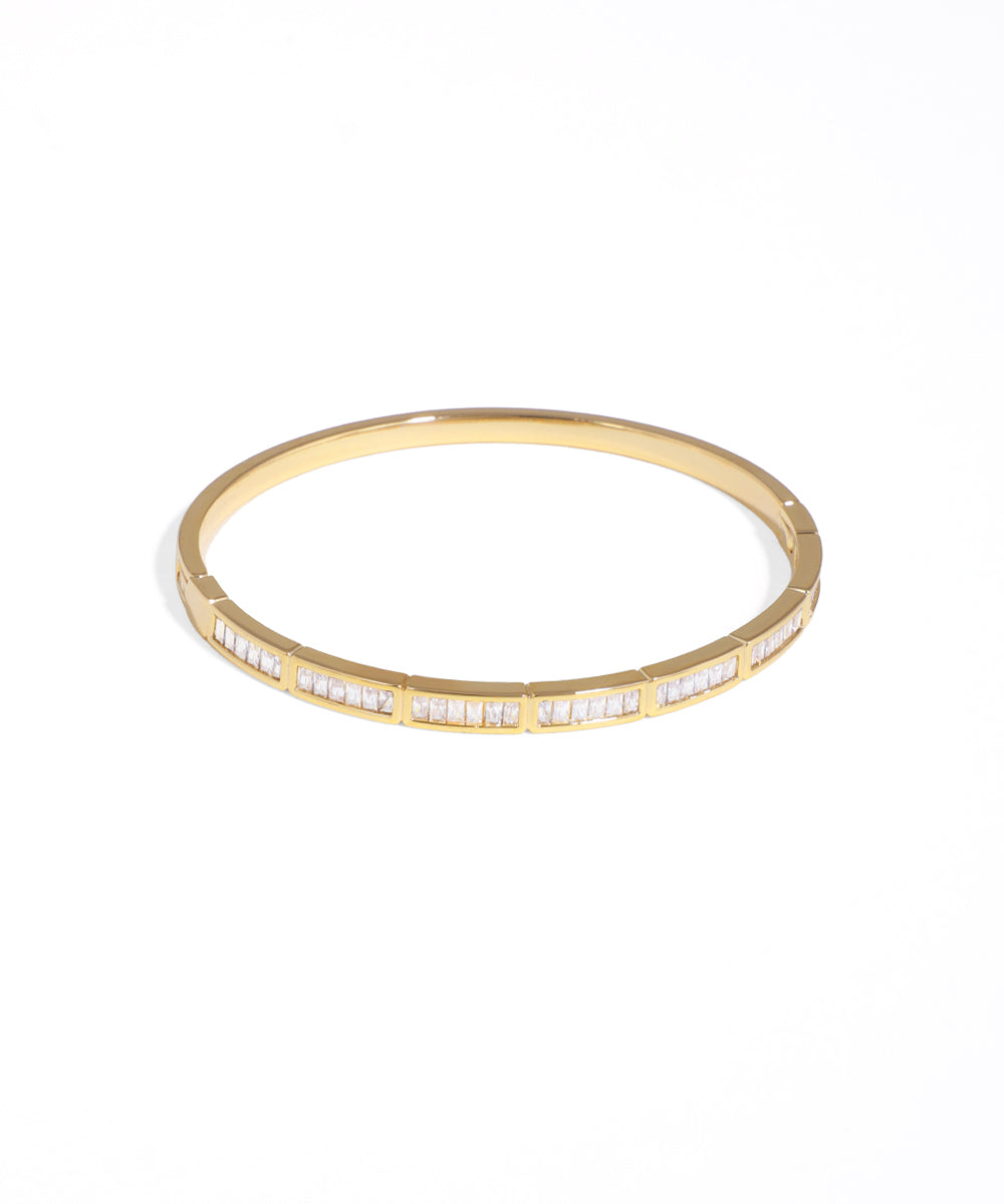 Gold bangle with embedded stones on a white background