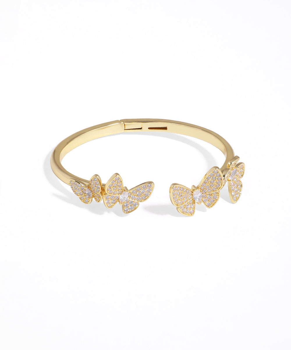 Gold bracelet with butterfly designs on a white background