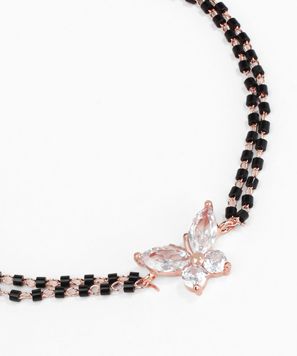 Necklace with black and rose gold beads and a butterfly pendant on a white background