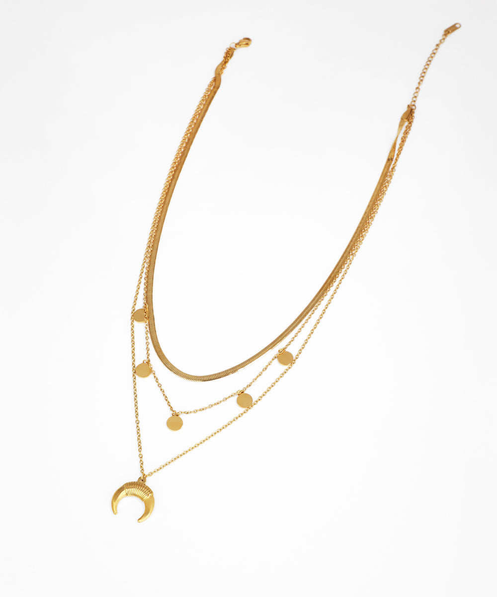 Gold necklace with multiple layers and a crescent moon pendant on a white background