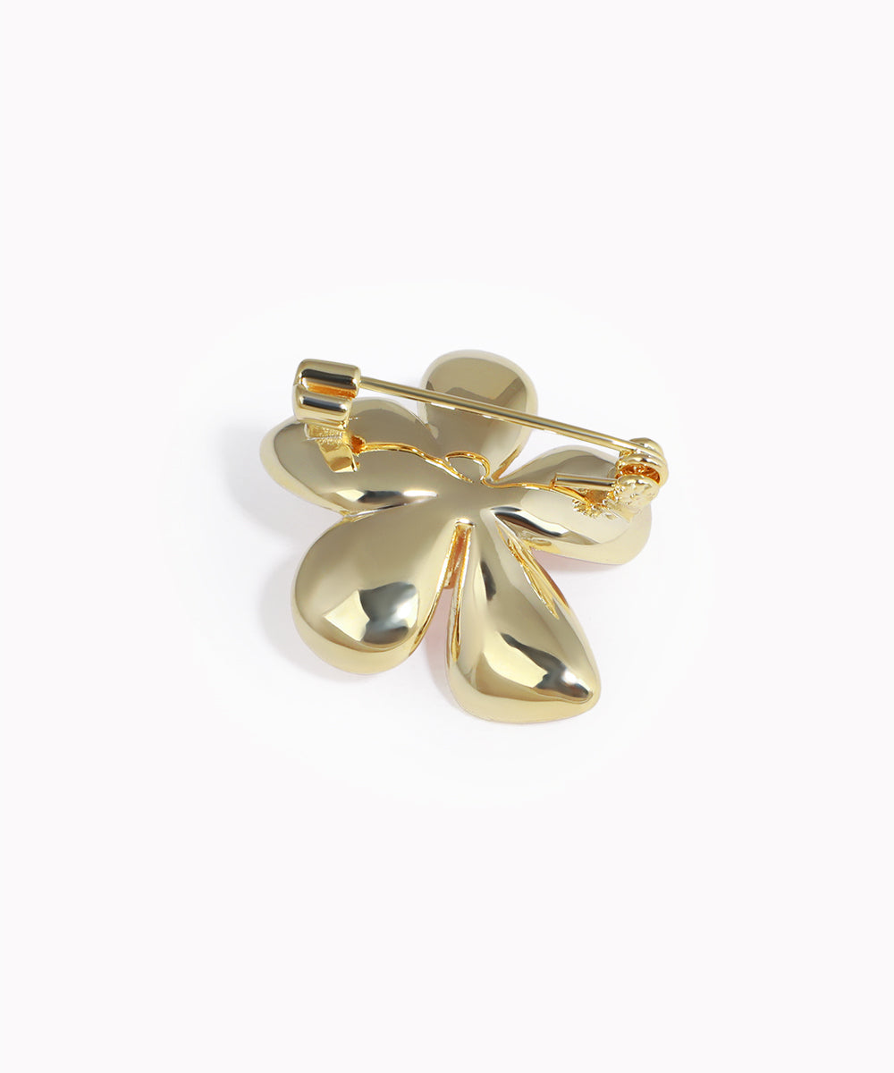 Gold four-leaf clover brooch on a white background