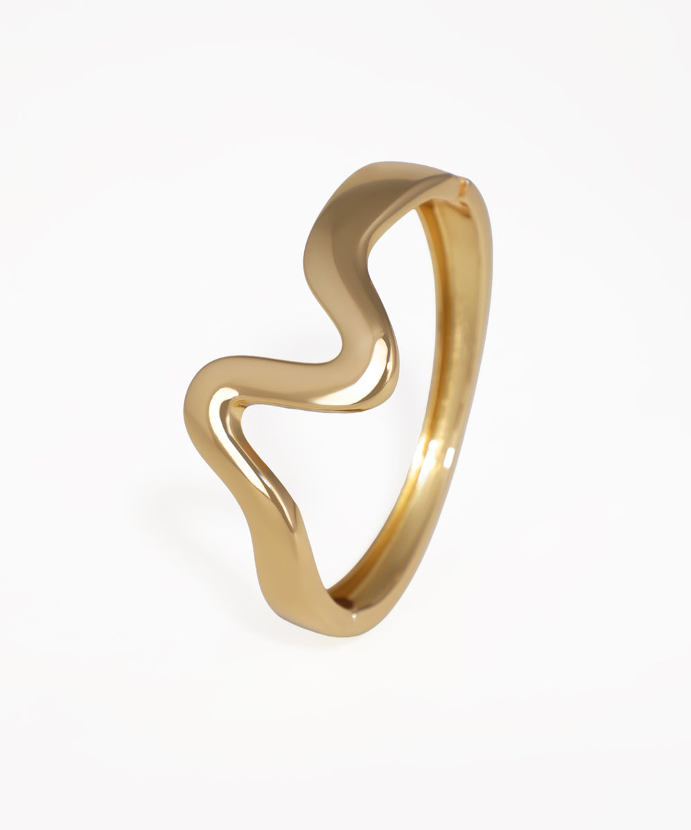 Gold ring with a wavy design on a white background