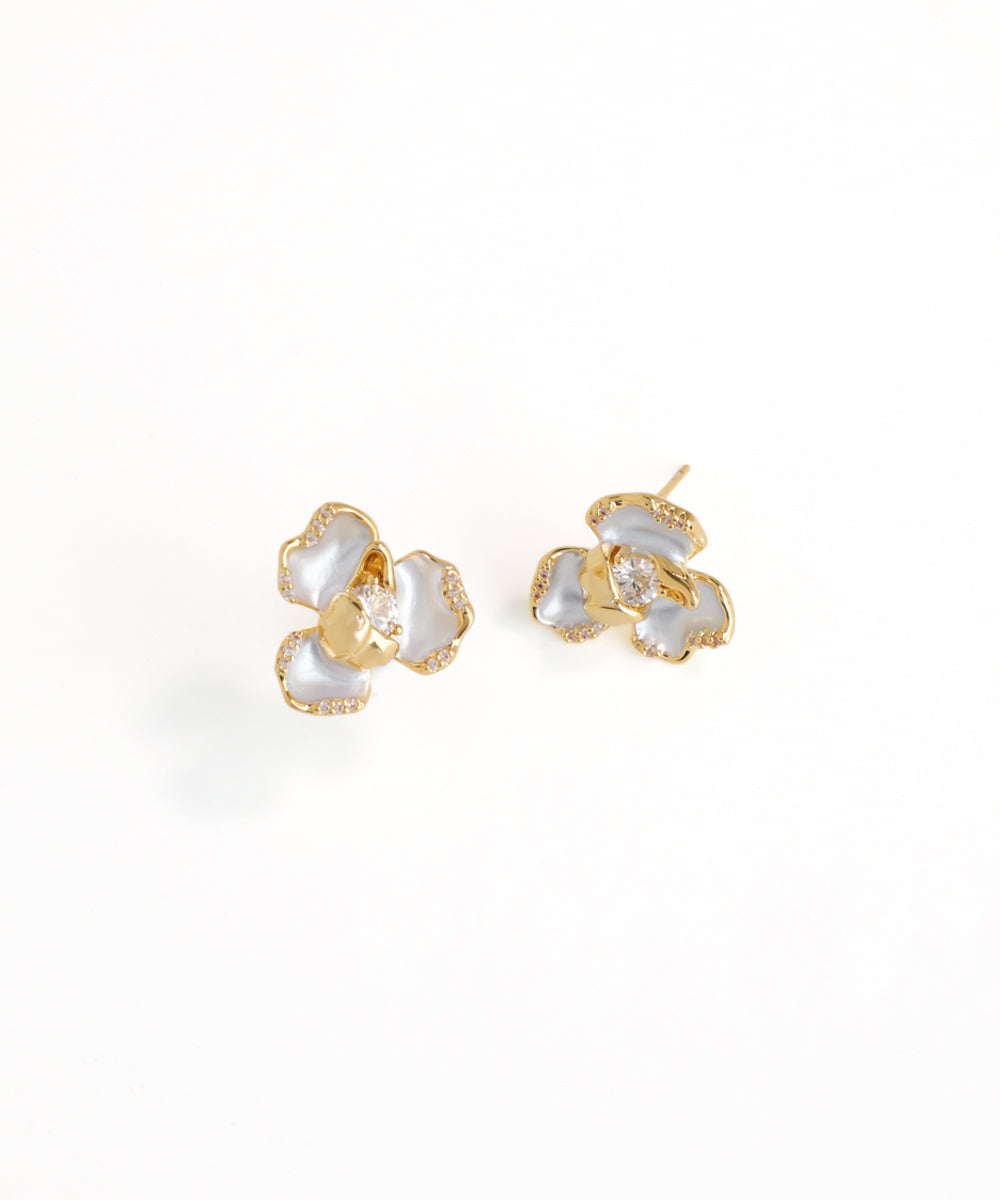 Gold and pearl flower-shaped earrings on a white background