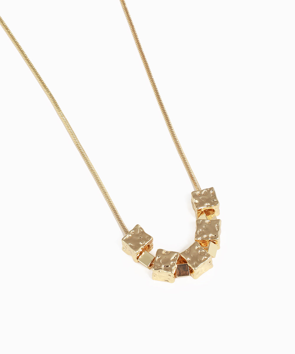 Gold necklace with geometric pendant on a white background