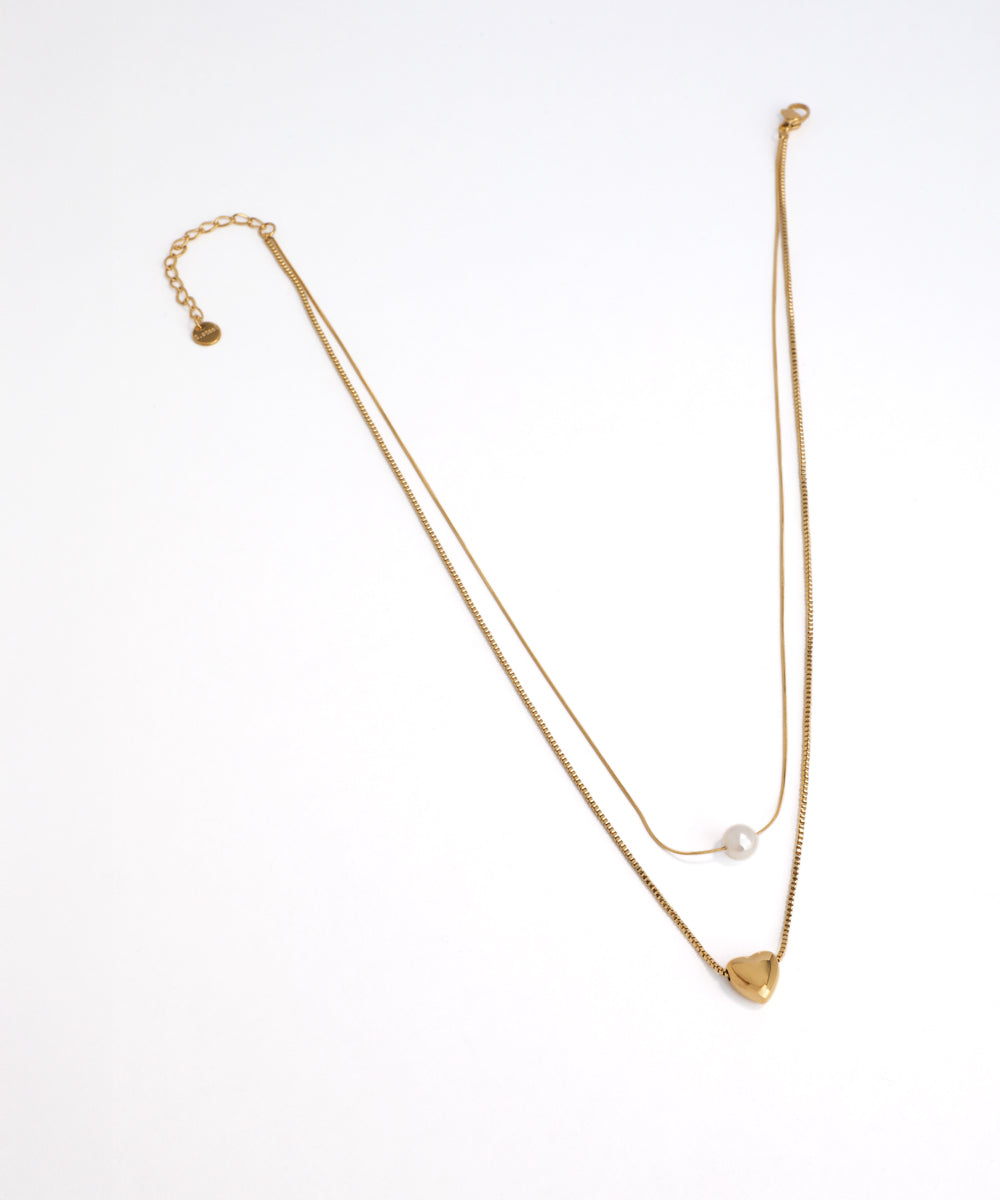 Gold necklace with heart pendant on a white background