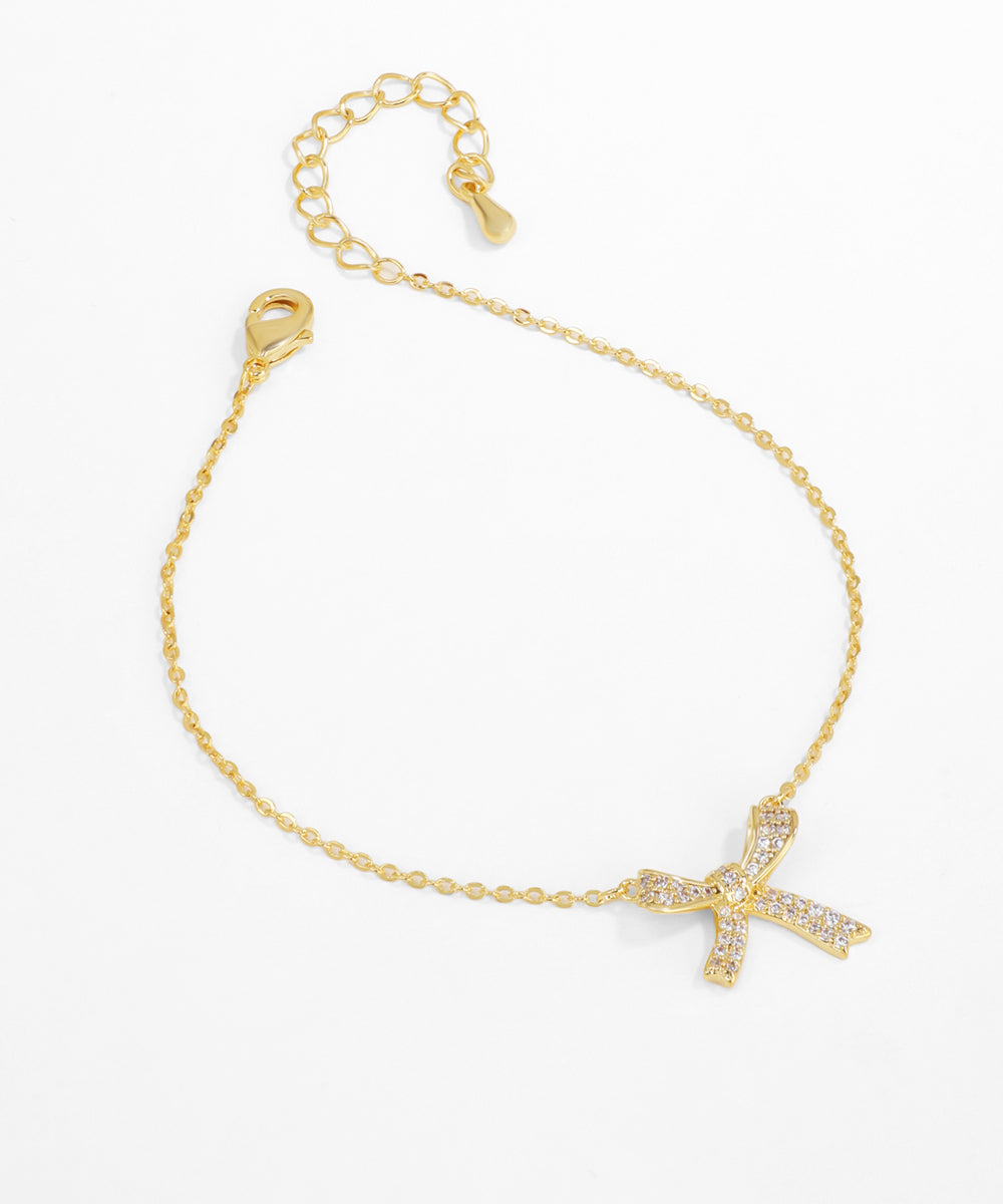 Gold bracelet with a bow-shaped clasp on a white background
