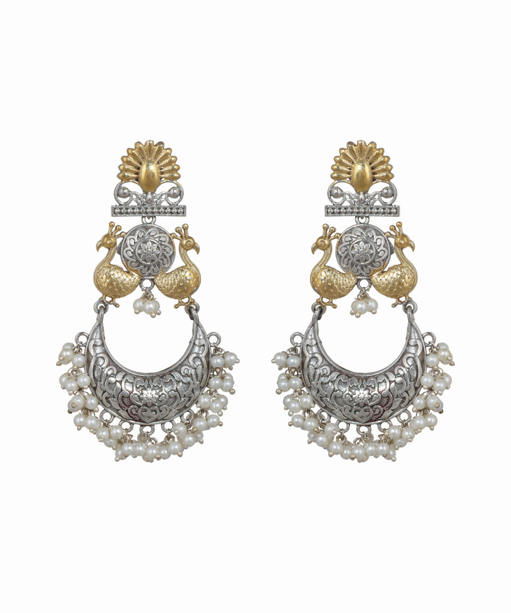 Pair of ornate earrings with gold and silver design on a white background