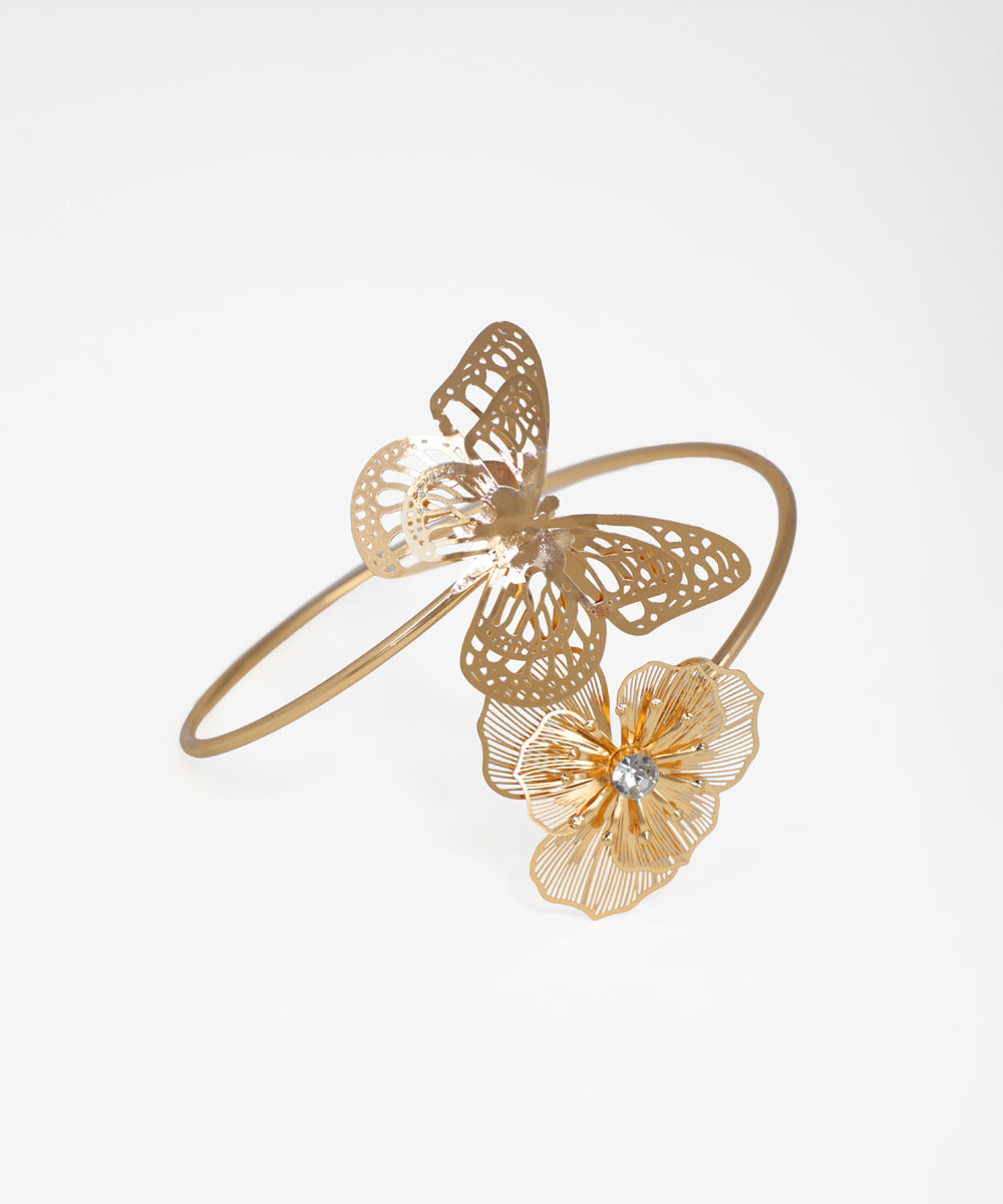 Gold bracelet with butterfly and flower design on a white background