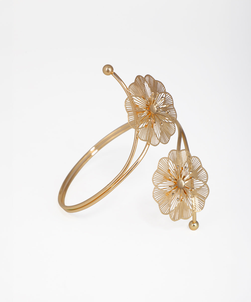 Gold bracelet with floral designs on a white background