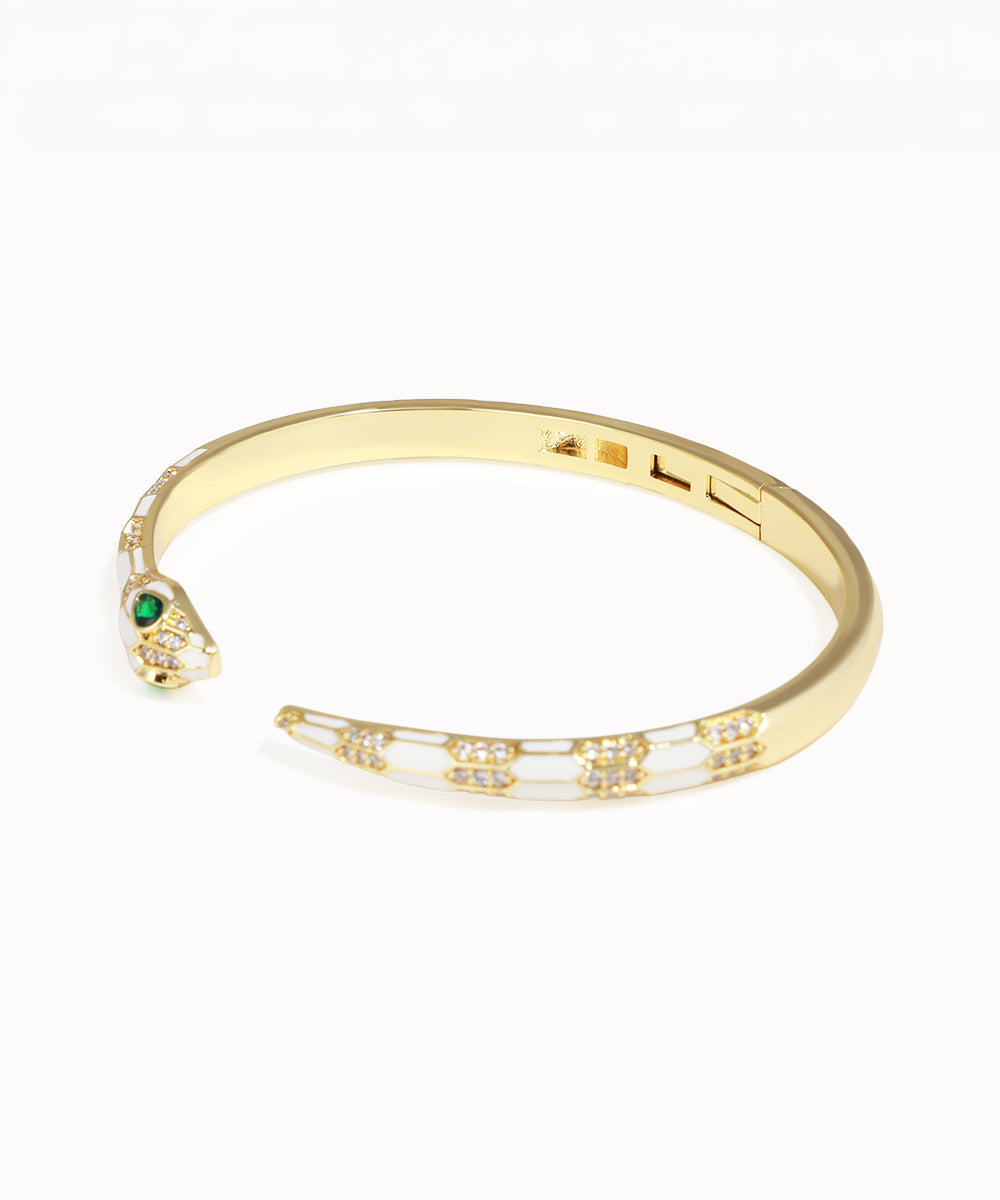Gold bracelet with a snake head design on a white background