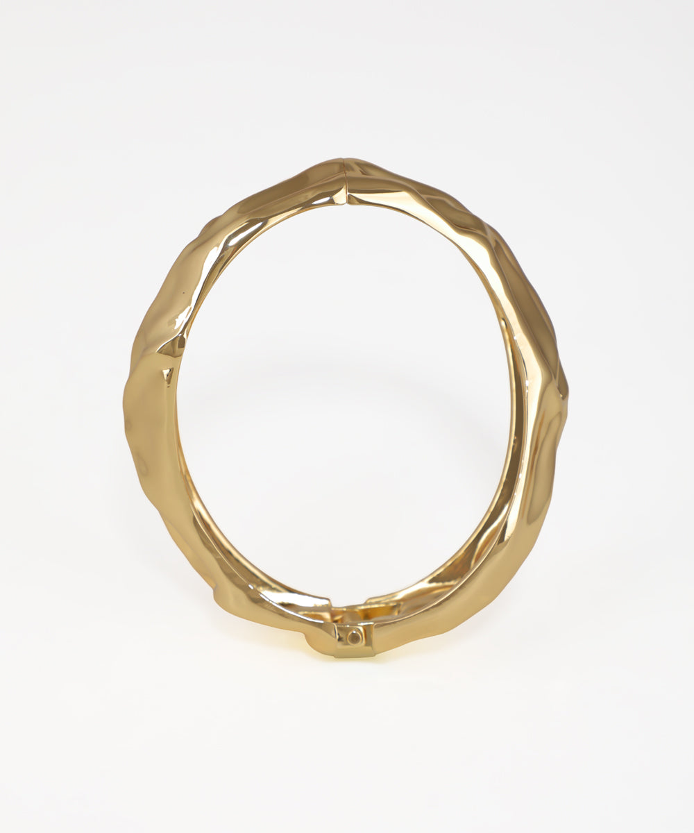 Gold ring with a textured design on a white background