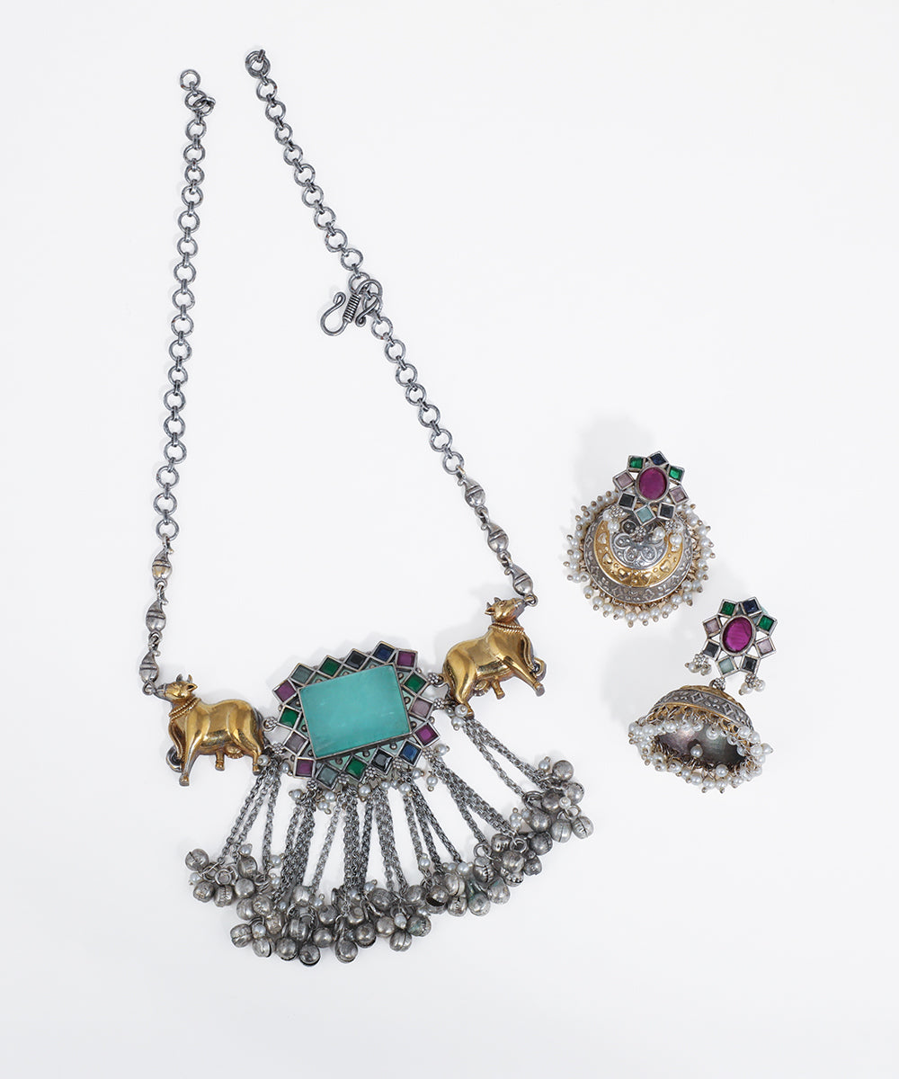 Oxidized silver-tone necklace with gold-tone Nandi bull motifs, blue-green stone, and ghungroo drops.